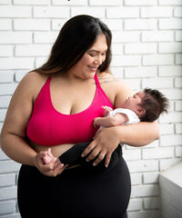 Woman wearing pink nursing bra holding a baby
