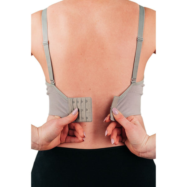 Back of woman wearing grey bra with hook and loop closure