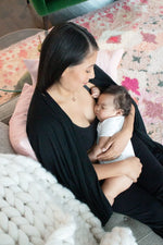 Woman wearing black open nursing cover while breastfeeding her baby