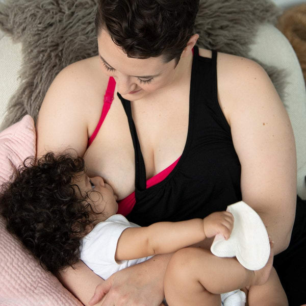 Woman breastfeeding her baby wearing black nursing nightgown and pink nursing bra
